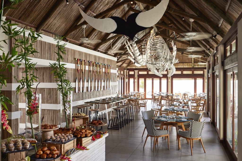 Restaurant im C Mauritius mit Holzbalkendecke, bunten Paddeln, Meerestier-Skulptur und Buffet mit Gebäck
