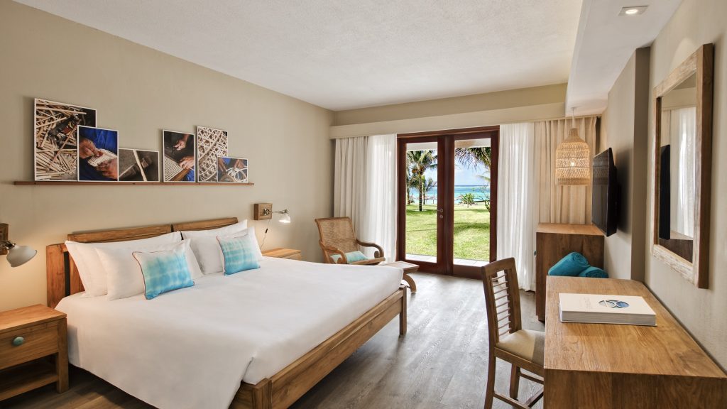 Prestige Room im C Mauritius mit großem Doppelbett, Holzmöbeln und Blick auf tropische Palmen und Meer
