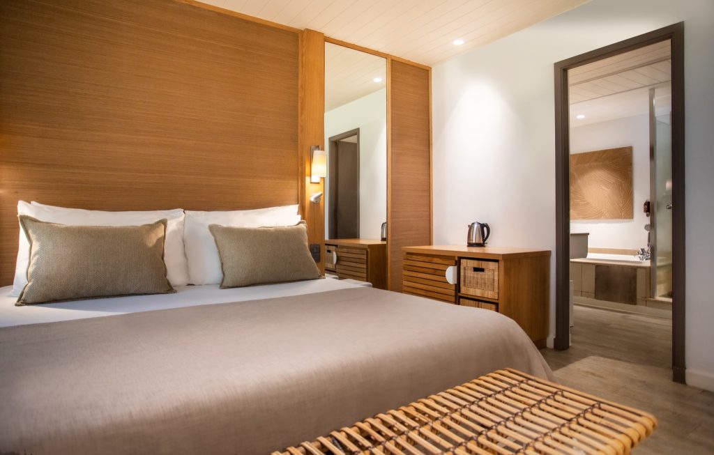 Modernes Family Zimmer im Canonnier Beachcomber Golf Resort & Spa mit Bett, Holzverkleidung und Badewanne in Mauritius