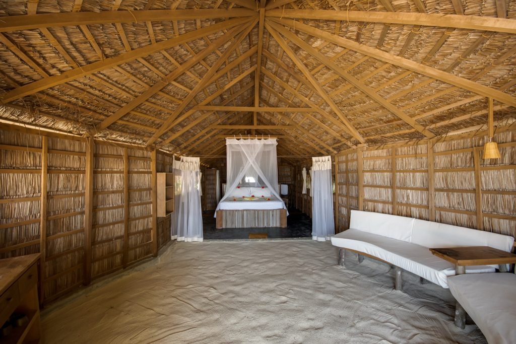 Innenraum eines tropischen Bungalows mit Bambuswänden, Baldachinbett mit Moskitonetz