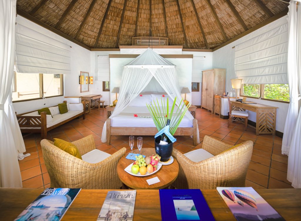 Geräumiges Zimmer der Beach Villa im Coco Palm Dhuni Kolhu mit Moskitonetzbett, Terrakottaboden und großen Fenstern