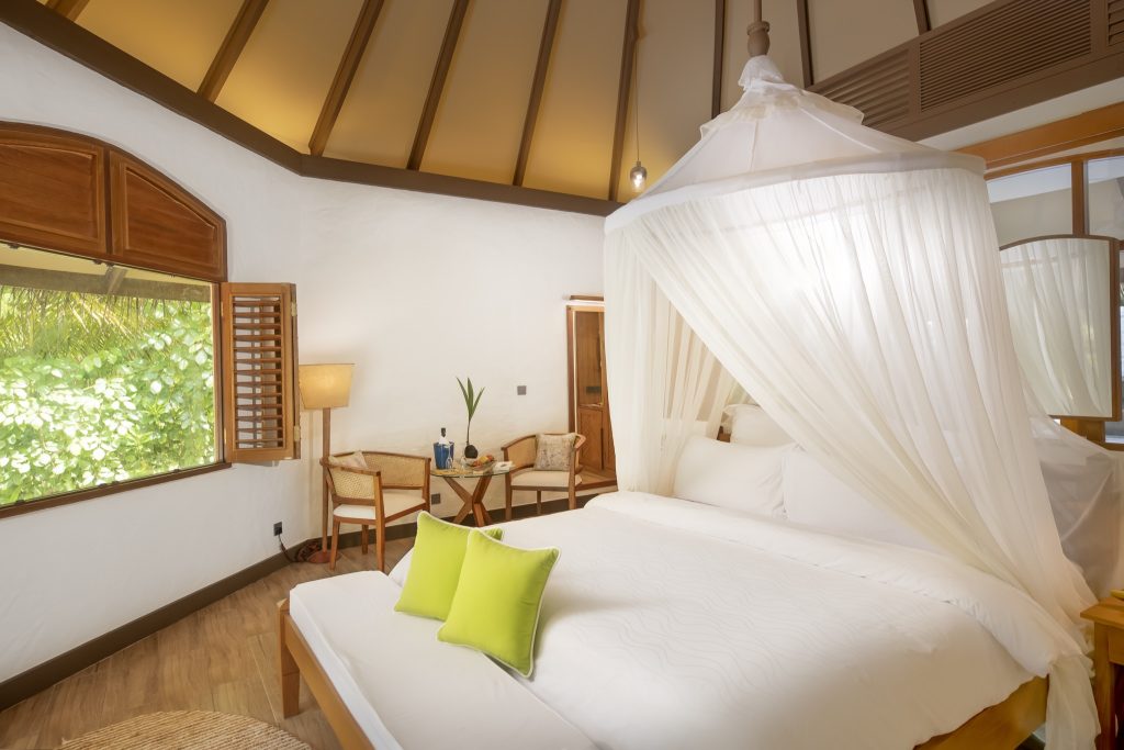 Hotelzimmer Deluxe Pool Villa mit Doppelbett, weißem Moskitonetz, grünen Kissen, Sitzecke