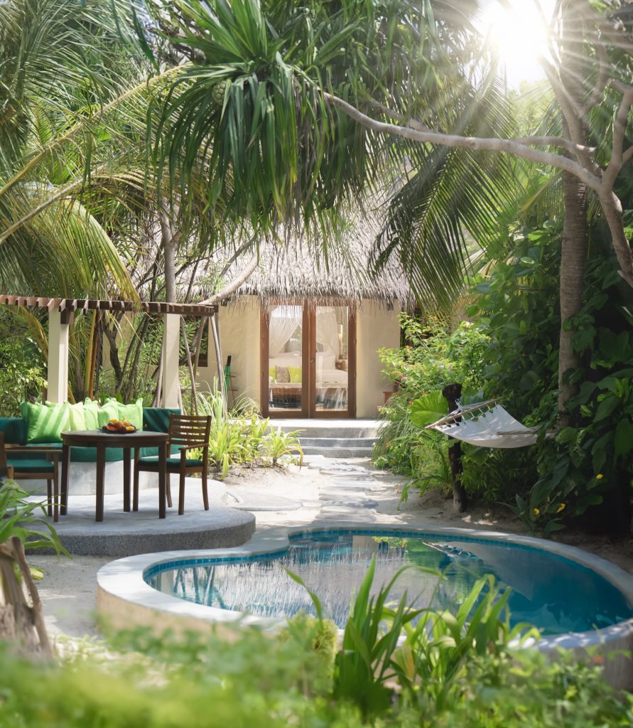 Geschwungener Pool vor deluxe pool villa mit Holz-Gartenmöbeln und Strohdach auf den