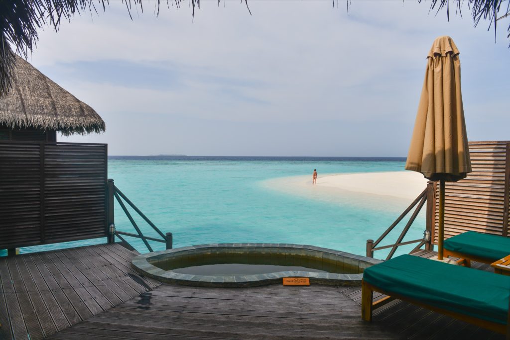 Terrasse der Lagoon Villa im Coco Palm Dhuni Kolhu mit Holzboden, zwei Liegestühlen, Sonnenschirm und kleinem Whirlpool