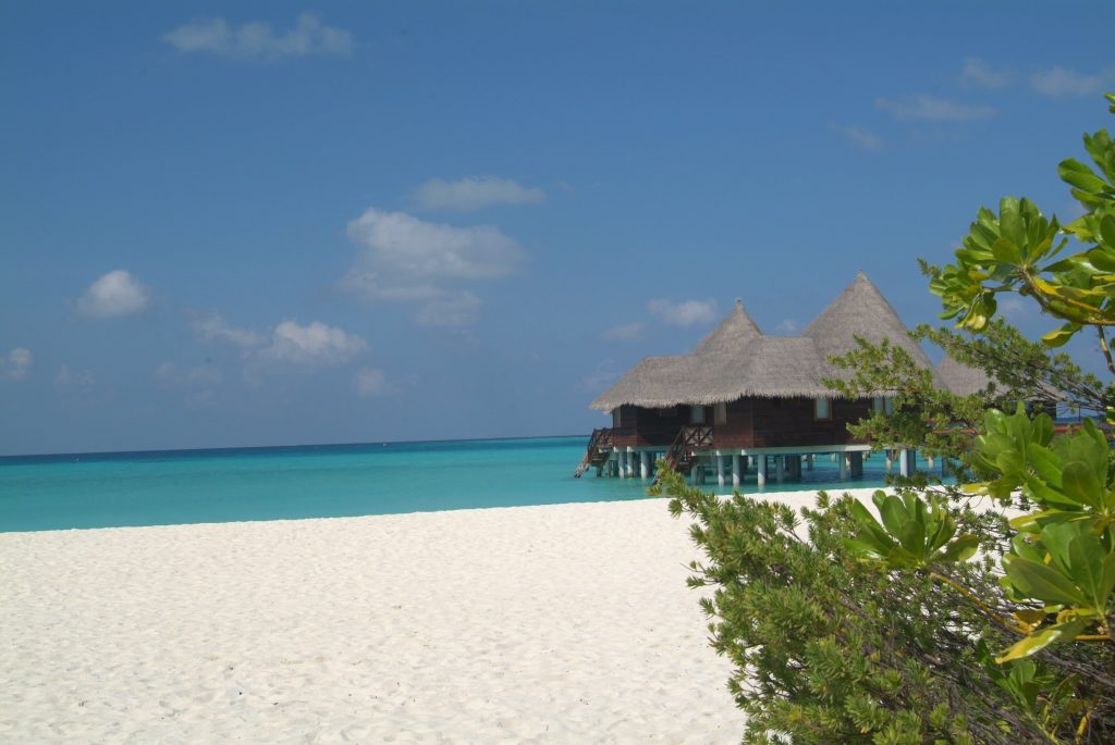 Lagoon Villa im Coco Palm Dhuni Kolhu auf Stelzen über türkisfarbenem Meer mit weißem Sandstrand und tropischem Holzbau