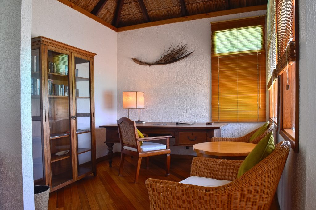 Lagoon Villa Zimmer mit Holzschreibtisch, Regal, Holzstuhl, grünen Kissen und Tageslicht in Coco Palm Dhuni Kolhu
