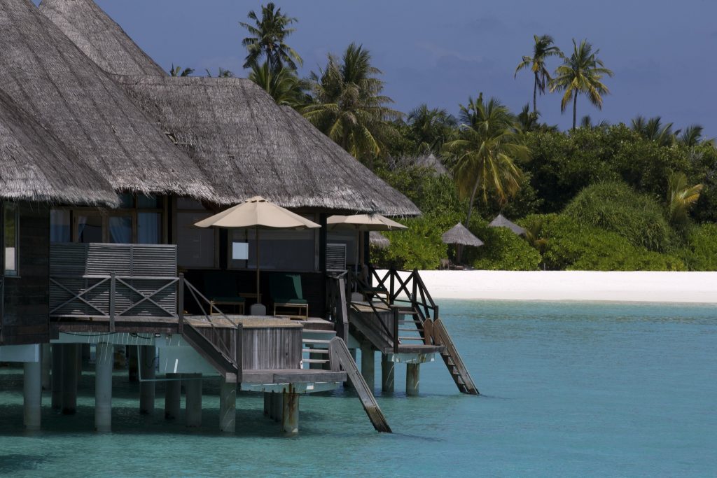 Overwater Bungalow der lagoon villa auf Pfählen über türkisfarbenem Wasser mit Schilfdach