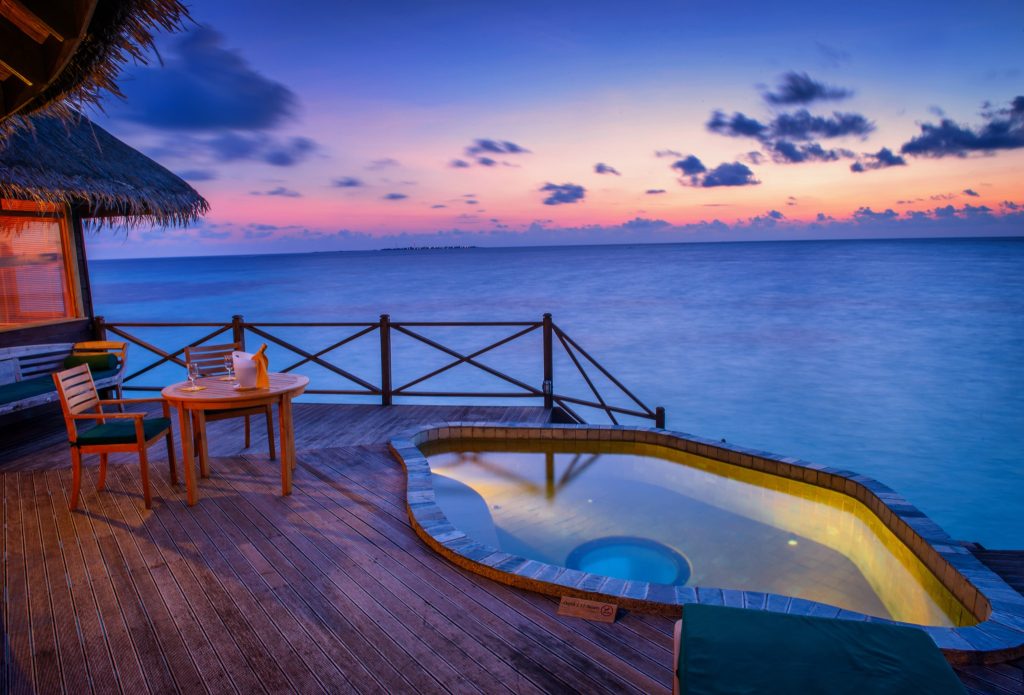 Veranda der Sunset Lagoon Villa mit Holztisch, Stühlen, kleinem Pool und Meerblick bei Dämmerung auf den
