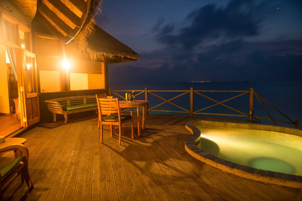 Holzterrasse der Sunset Lagoon Villa mit Holztisch, Stühlen, Sitzbank und kleinem Pool bei Dämmerung auf den