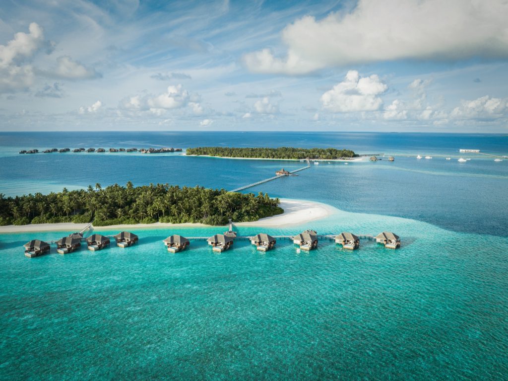 Luftaufnahme des Conrad Maldives Rangali Island Resorts mit Wasserbungalows auf Pfählen und tropischer Insel im Hintergrund