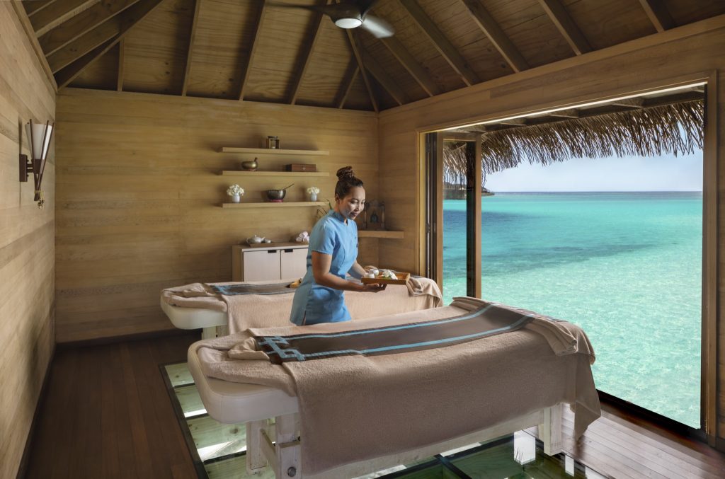 Massagebereich mit zwei Betten, Holzinterieur und Glasboden mit Blick auf den Ozean bei Conrad Maldives Rangali Island