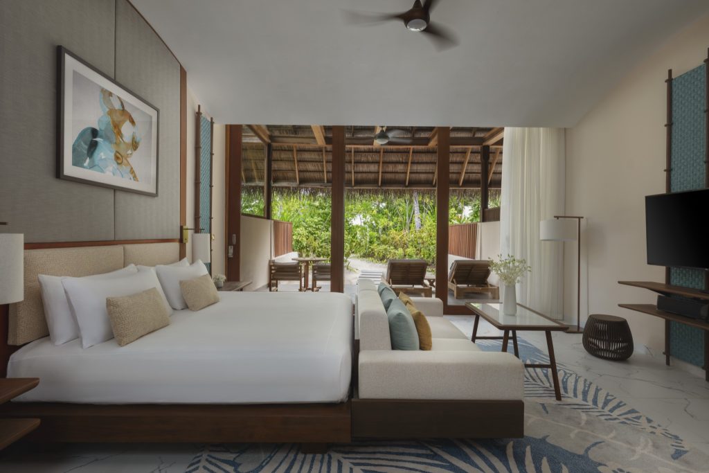 Zimmer der Beach Villa im Conrad Maldives Rangali Island mit großem Bett, Holzmöbeln und Terrasse