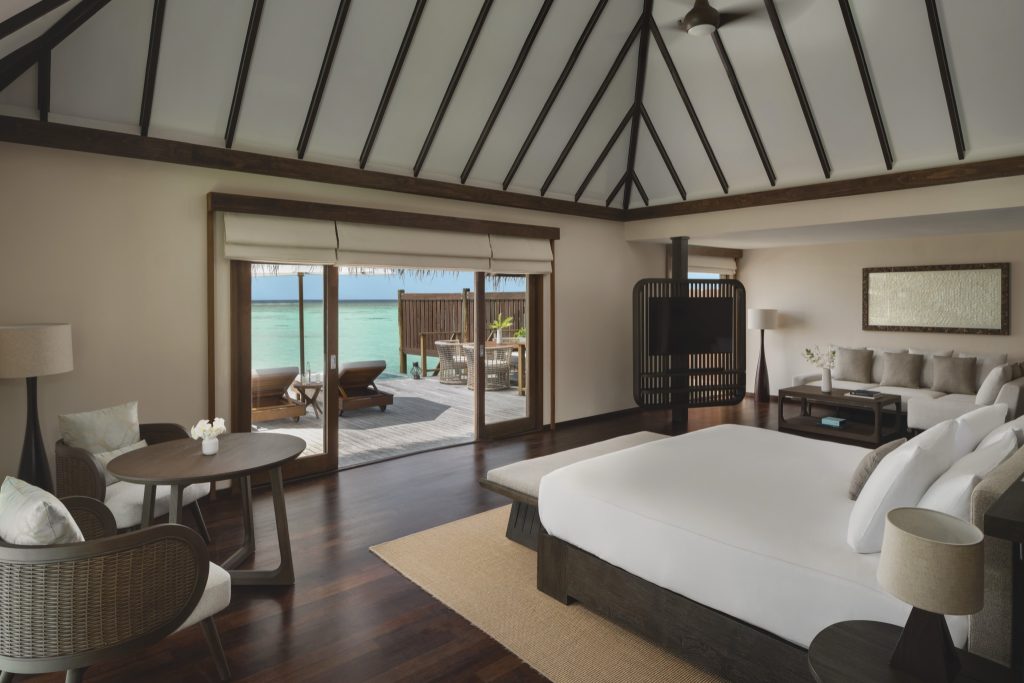 Hotelzimmer Premiere Water Villa mit großem Bett, Sofa, Couchtisch, Fensterfront zur Holzterrasse