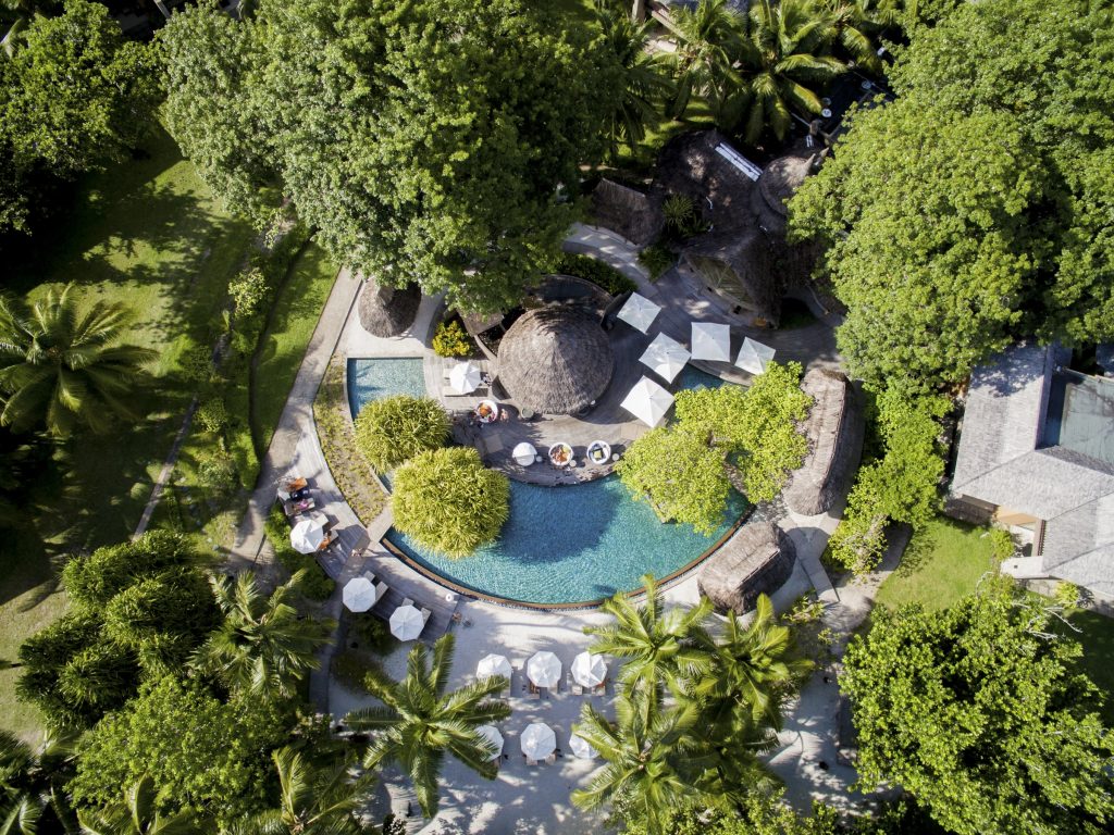Vogelperspektive auf Constance Ephelia Pool mit blauem Wasser, strohgedeckten Pavillons und weißen Sonnenschirmen