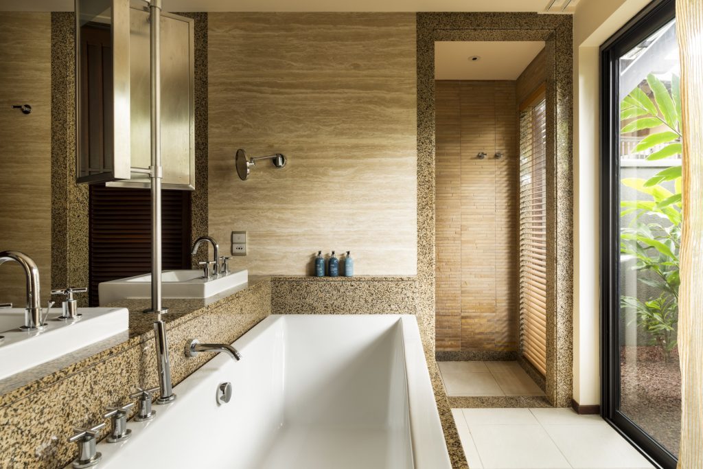 Modernes Badezimmer in der Junior Suite mit freistehender Badewanne, Chromarmaturen und Natursteinwänden