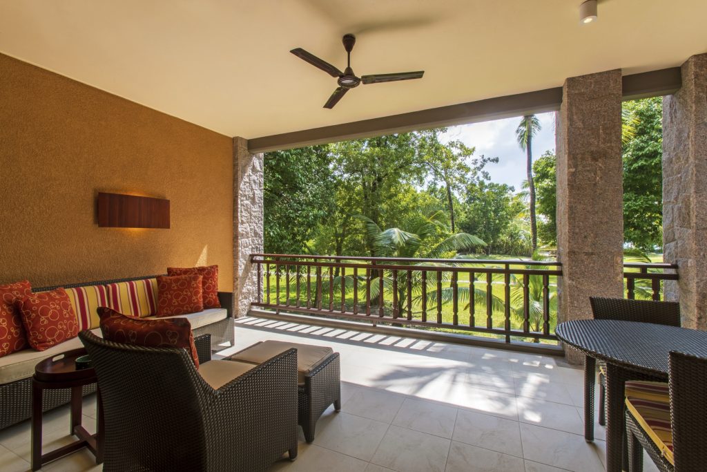 Überdachte Terrasse der Senior Suite im Constance Ephelia mit dunklen Rattanmöbeln und bunten Kissen