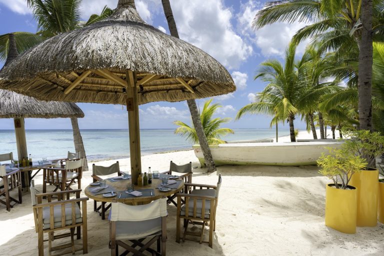 Terrasse des Restaurants Le Morne mit Holztischen und strohgedeckten Sonnenschirmen am Strand von Mauritius