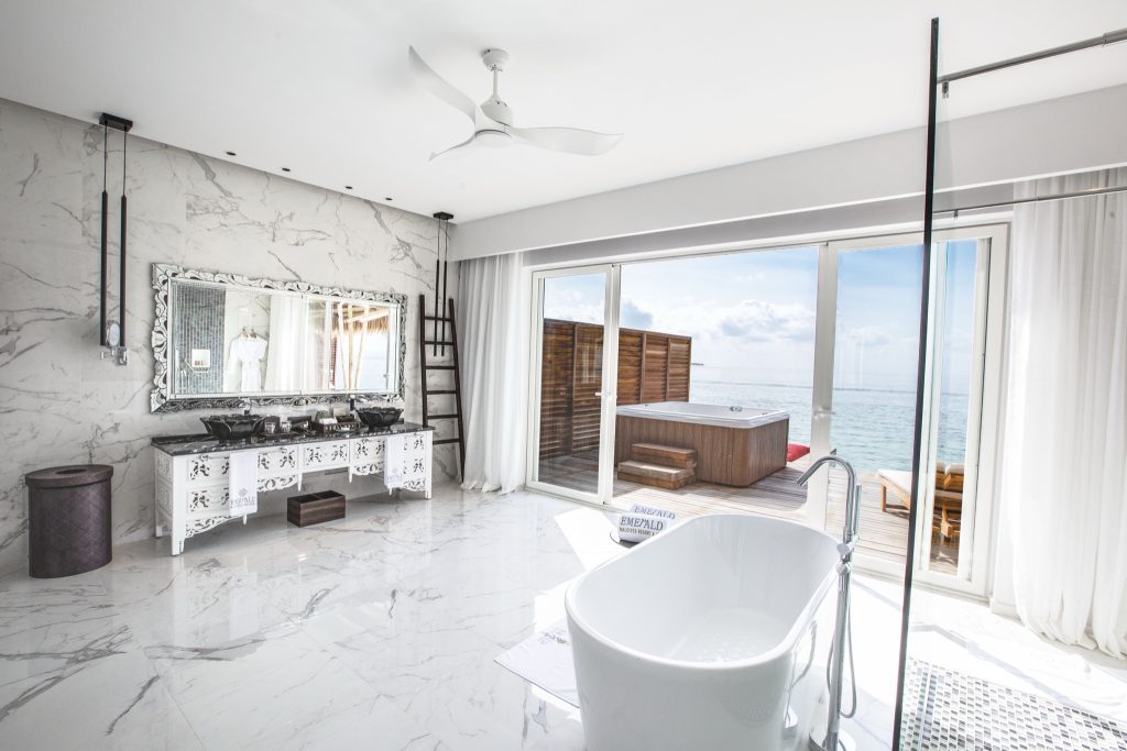 Modernes Badezimmer mit Marmorfliesen, freistehender Badewanne und Terrasse mit Holzjacuzzi und Meerblick im Emerald.