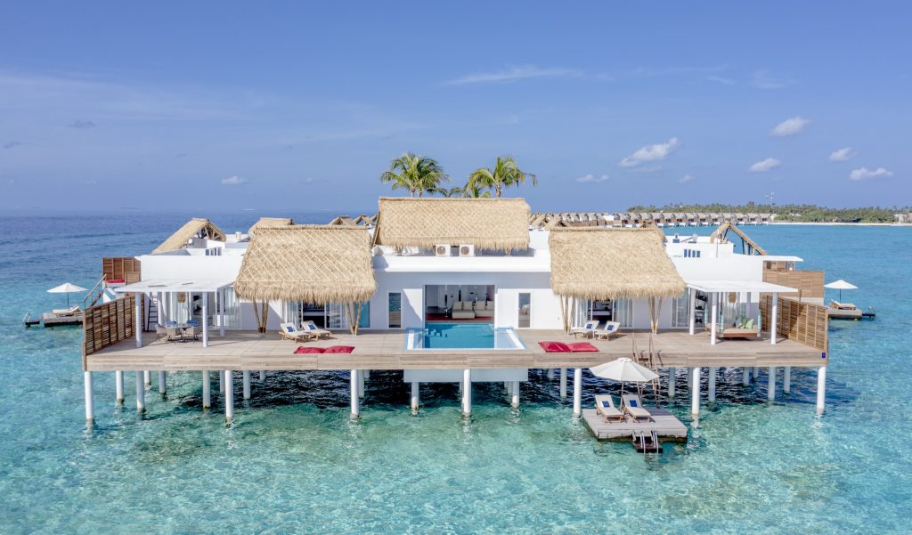 Prächtige Presidential Water Villa mit weißen Wänden, Strohdächern und Pool auf Stelzen über türkisblauem Wasser