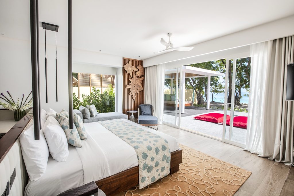 Modernes Hotelzimmer der Royal Beach Villa mit Glas-Schiebetüren, Terrasse und natürlicher Einrichtung im Emerald Maldives.