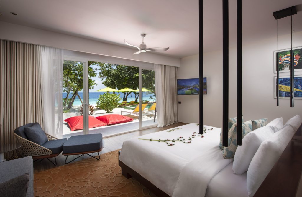 Modern eingerichtetes Zimmer Royal Beach Villa mit großem Bett, Sessel und Meerblick bei Tageslicht
