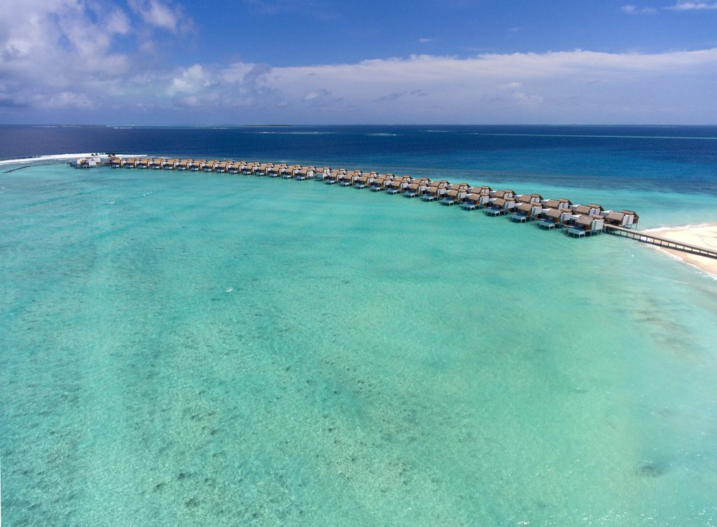 Reihe von Wasserbungalows auf Stelzen über türkisfarbenem Ozean im Emerald Maldives Resort & Spa