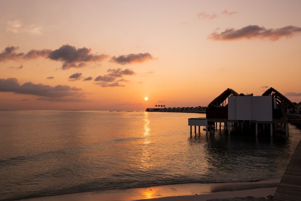 Water Villa mit Pool auf Stelzen über dem Meer bei Sonnenuntergang im Emerald Maldives Resort & Spa