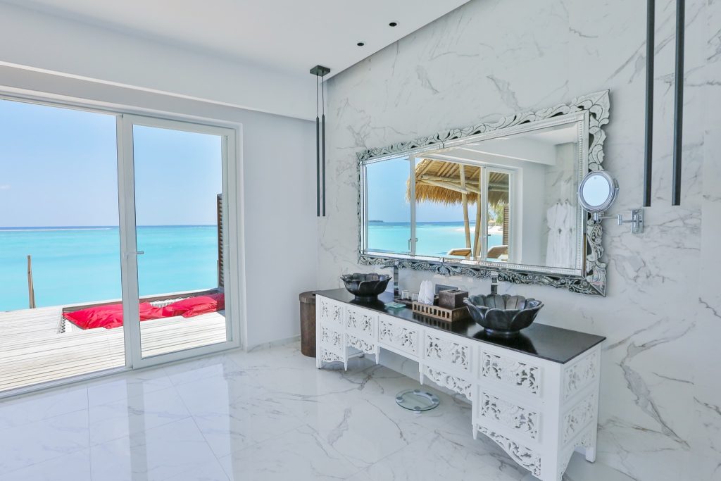 Hotelzimmer Water Villa mit weißem Marmor, Sideboard mit geschnitzten Waschbecken und Meerblick auf den