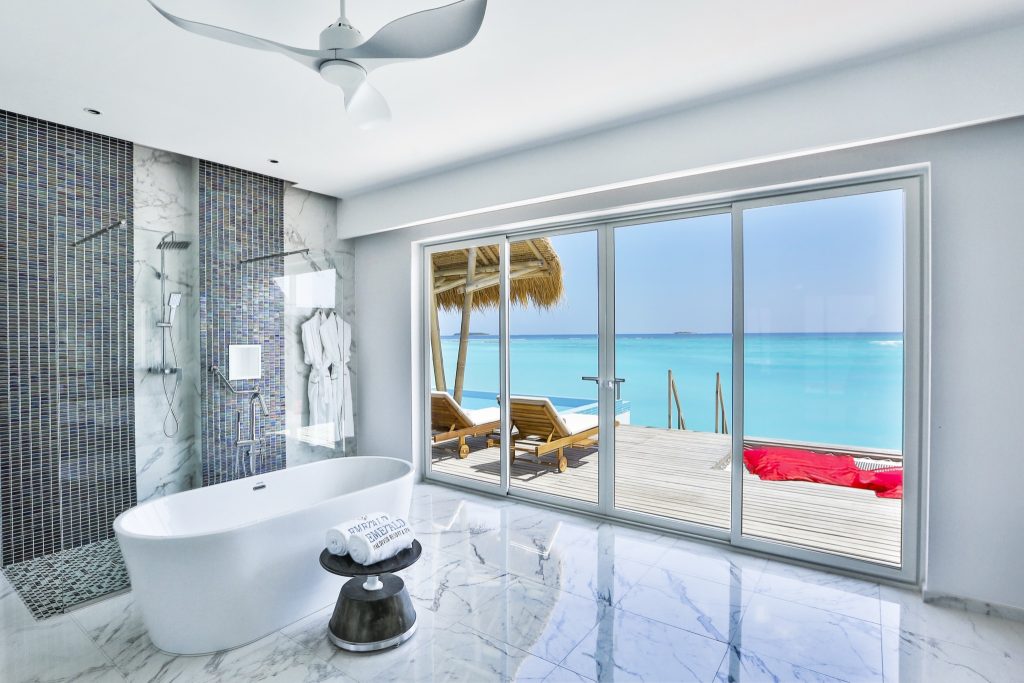 Modernes Badezimmer mit freistehender Badewanne, Marmorboden und Terrasse mit Meerblick im Emerald Maldives Resort & Spa