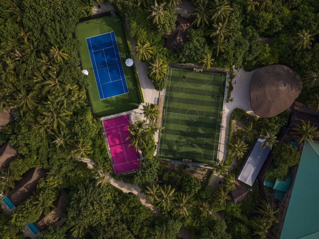 Luftaufnahme der Sportanlagen im Finolhu Baa Atoll Maldives mit Tennis- und Fußballplätzen umgeben von Palmen und dichter.