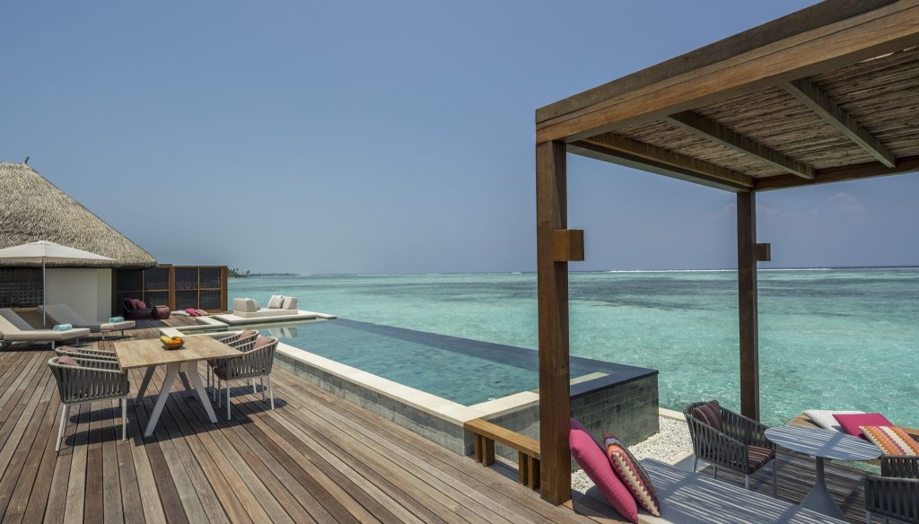 Terrasse mit hellem Holzfußboden, Pergola, geflochtener Sitzgruppe und Pool mit Blick auf das Meer auf den