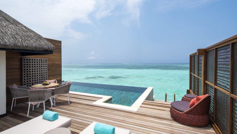 Terrasse mit Holzboden, Infinity-Pool und Sitzgruppen mit türkisfarbenen Handtüchern am Meer