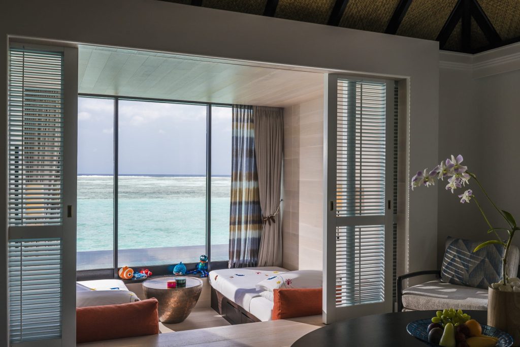 Hotelzimmer mit großem Fenster, Meerblick, zwei Liegeflächen mit bunten Kissen