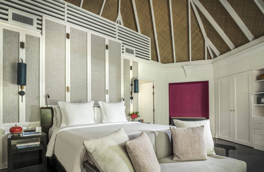 Hotelzimmer mit großem weißen Bett, Holzbalkendecke, zwei Nachttischen und einer roten Wandnische