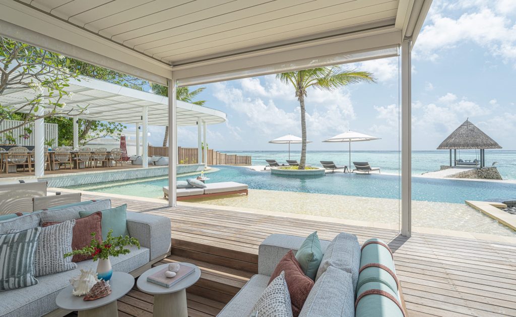 Offener Hotelbereich mit Infinity-Pool, hellen Holzelementen, Pastellmöbeln und Meerblick im Four Seasons Kuda Estate