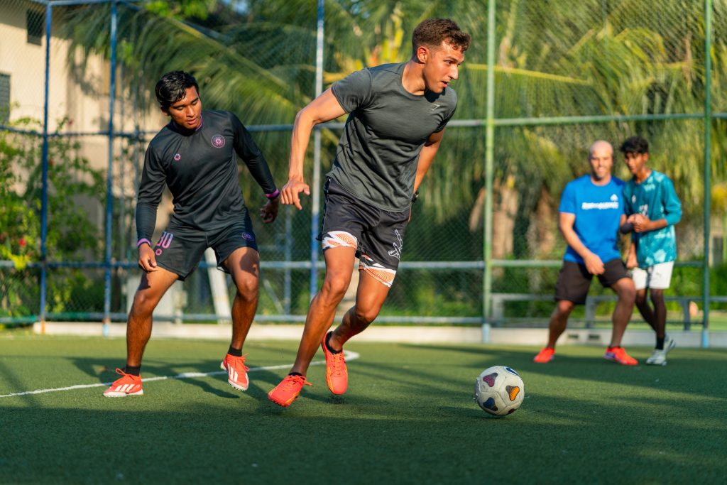 Fußballspiel mit vier Spielern auf grünem Kunstrasen im Four Seasons Resort Maldives at Landaa Giraavaru