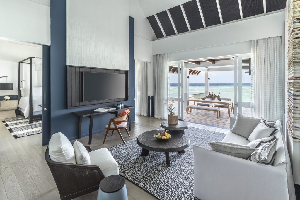 Helles Zimmer der Villa mit Couch, Couchtisch, Schreibtisch, Fernseher und Terrasse mit Meerblick