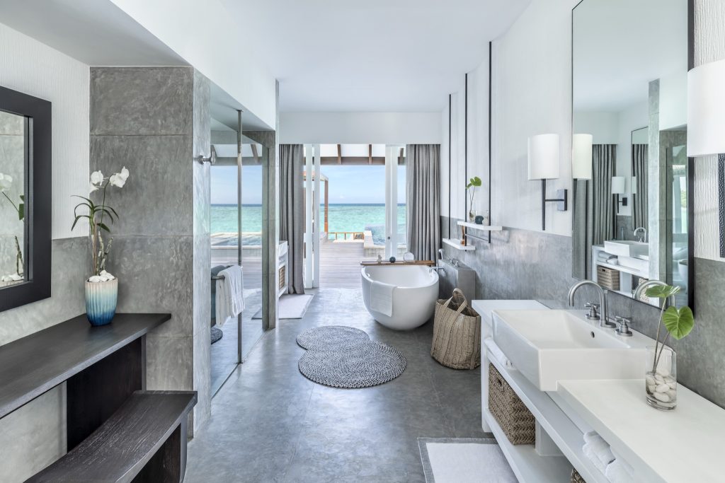 Badezimmer mit weißem Waschbecken auf Holzkommode, freistehender Badewanne und Meerblick im Four Seasons Landaa Giraavaru