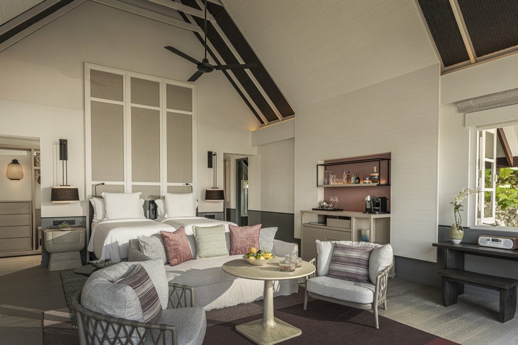 Geräumiges Hotelzimmer mit zwei Betten, Sitzecke, Minibar und großen Fenstern im Four Seasons Resort Maldives