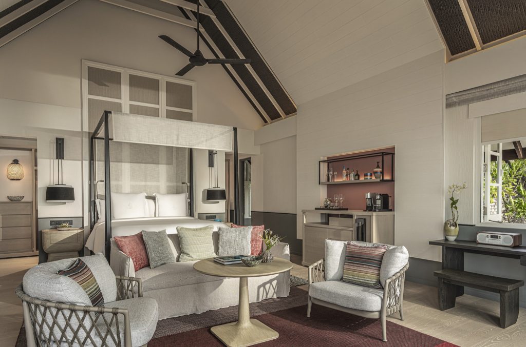Modernes Hotelzimmer mit Himmelbett, runder Tisch, Sesseln, Holzelementen und Tageslicht