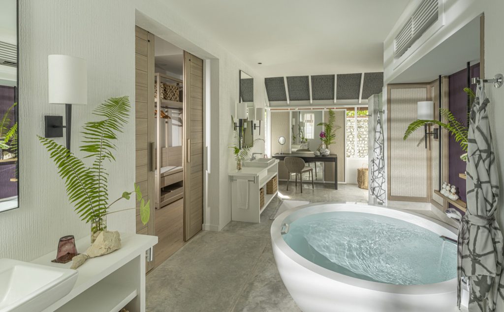 Modernes Badezimmer mit ovaler Badewanne, grauen Steinfliesen, Waschtisch und grünen Pflanzen im Four Seasons Resort Maldives