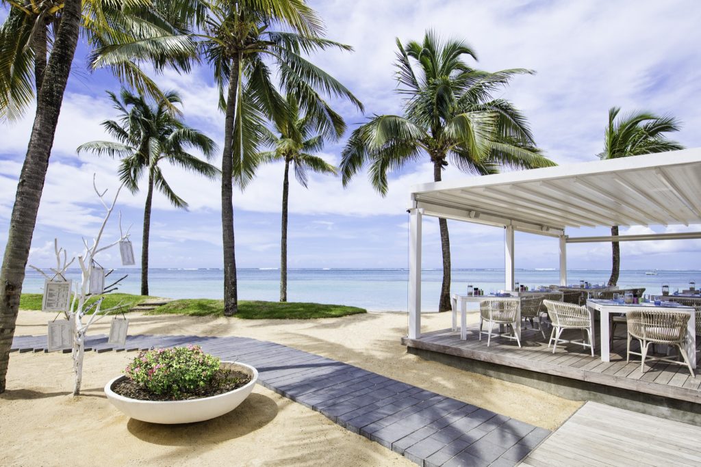 Offene Terrasse des Restaurant Le Palmier mit weißen Tischen, geflochtenen Stühlen und Blick auf das Meer in Mauritius