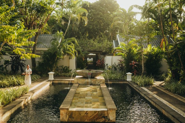 Hotelgarten mit rechteckigem Steinkunstbrunnen und tropischen Palmen im Seven Colours Spa, Heritage Le Telfair Mauritius
