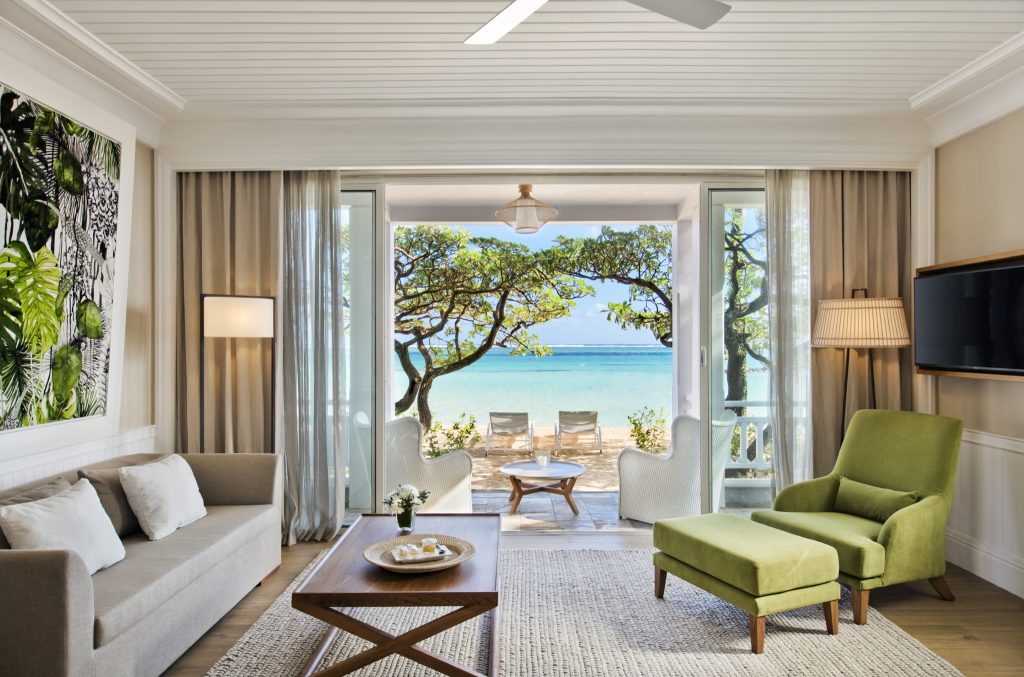 Deluxe Beachfront Suite im Heritage Le Telfair mit Sofa, grünem Sessel, Terrasse und Meerblick in Mauritius
