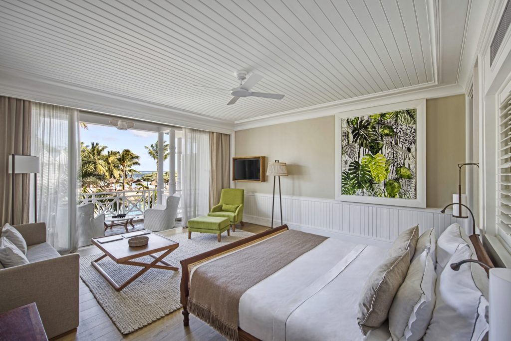 Deluxe SeaView Suite Zimmer mit großem Bett, grünem Sessel, Holztisch und Balkon mit Meerblick in Mauritius
