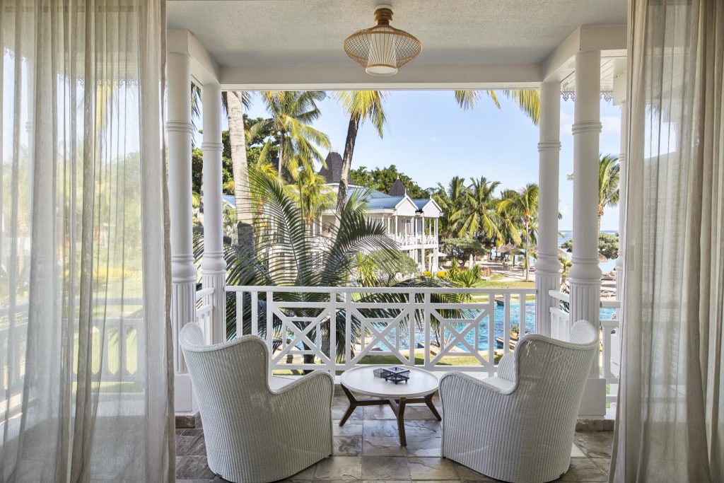 Veranda der Heritage Le Telfair Deluxe Seaview Suite mit zwei weißen Korbsesseln, kleinem Tisch und tropischem Ausblick