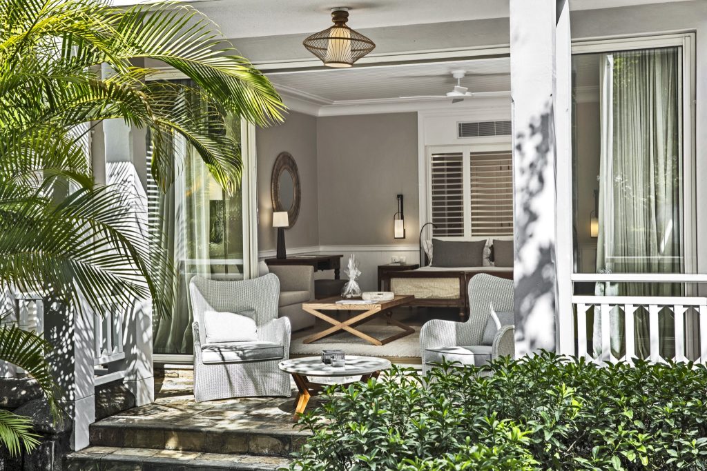 Hotelveranda mit zwei hellen, geflochtenen Sesseln und Holztisch, Blick in moderne Sitzecke der Deluxe Suite Garden