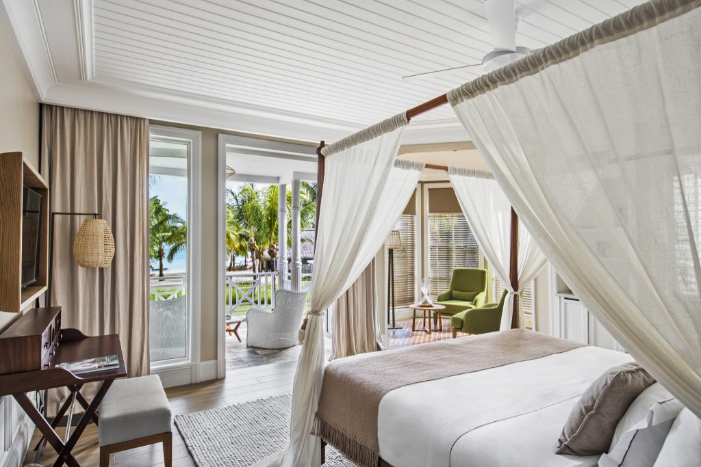 Helles Hotelzimmer Heritage Le Telfair Junior Suite Garden View mit Himmelbett, weißen Vorhängen und Terrasse