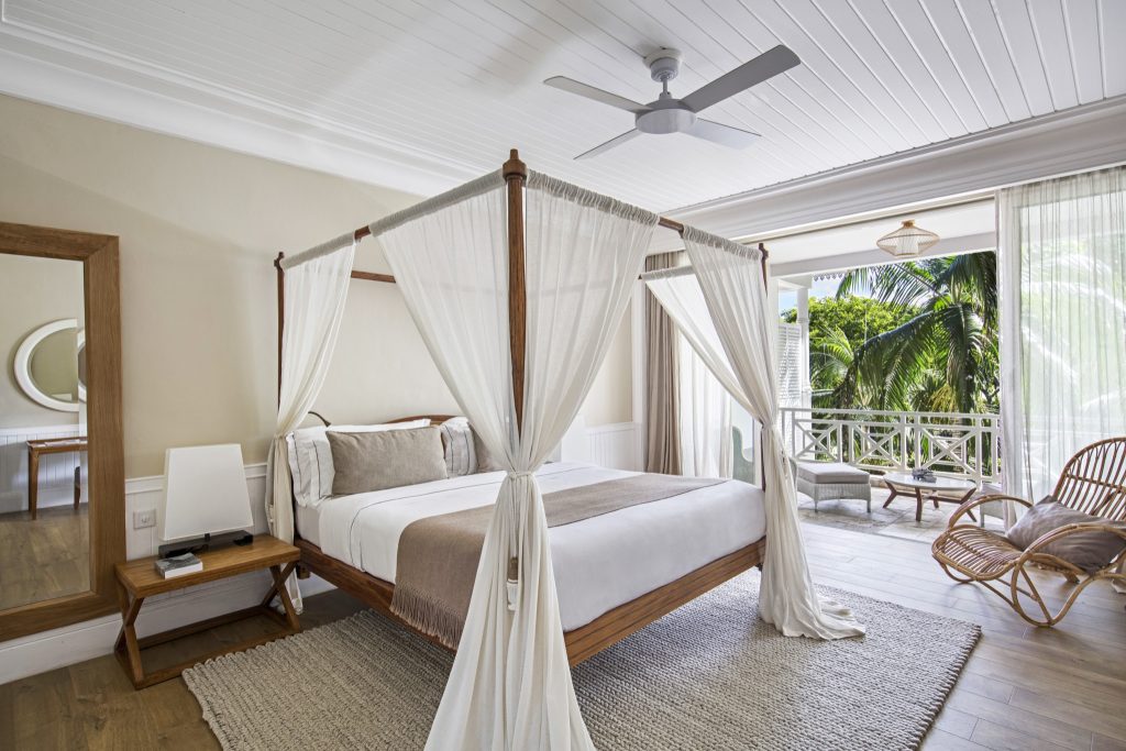 Senior Suite Garden View Zimmer mit Himmelbett, weißen Vorhängen, Holzboden und Balkon mit Palmenblick