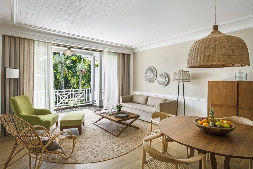 Hotelzimmer Senior Suite Garden View mit Balkon, Holztisch, Obstschale, Couch, Stehlampe und Naturfaserteppich